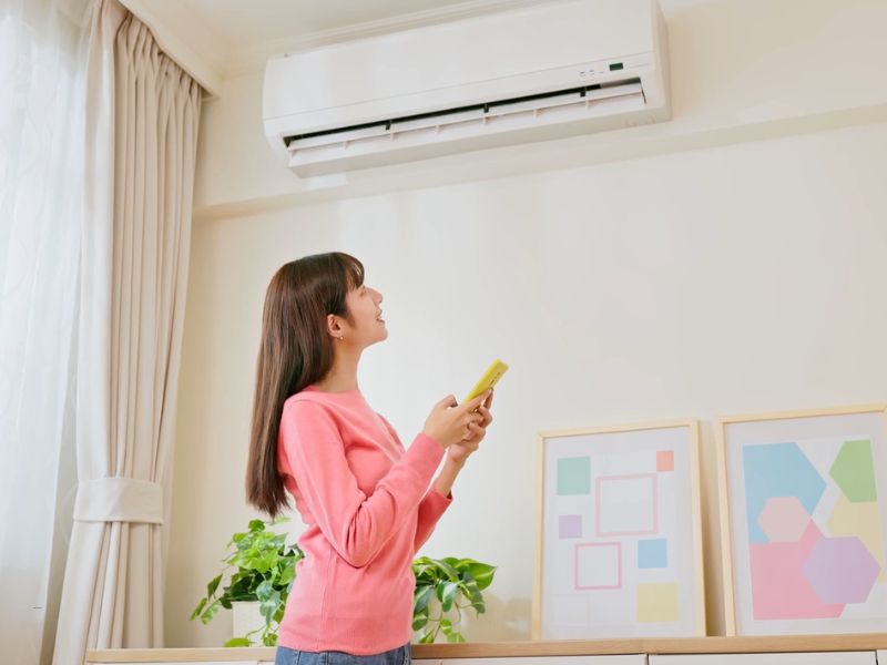 devojka podešava klima uređaj preko telefona
